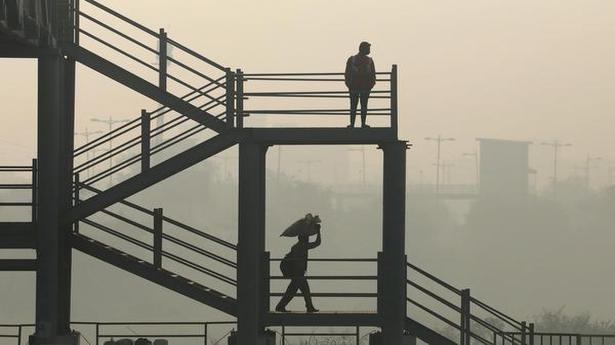   Men are seen on a skywalk near Delhi-Meerut Expressway on a smoggy day in New Delhi on October 30, 2020.  