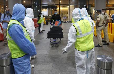 Municipal workers in protective gear wait for passengers arriving from the U.K. at the Chhatrapati Shivaji Maharaj International Airport in Mumbai on December 22, 2020.