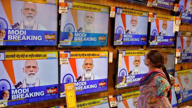   A woman wearing a protective mask watches Prime Minister Narendra Modi's address to the nation, in Ahmedabad on October 20, 2020.  